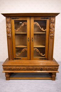 Masivní vitrína s vyřezávanými postavami a dekorativními prvky