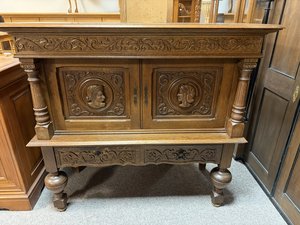 Příborník s reliéfními portréty ve dveřích a řezaným ornamentem