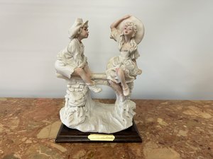 Porcelánová soška páru na lavičce, na dřevěném podstavci