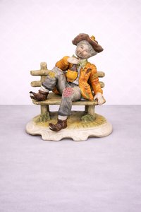 Porcelánová soška odpočívajícího hudebníka