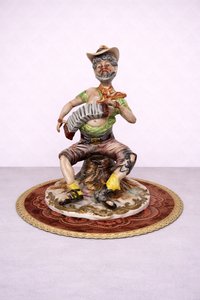 Porcelánová soška hudebníka s harmonikou