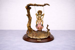 Soška dětí na houpačce u stromu s rustikálním podstavcem