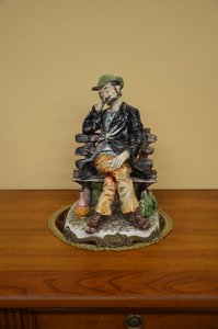 Porcelánová soška muže odpočívajícího na lavičce