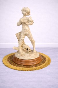Soška chlapce s ptáčkem na ozdobném podstavci