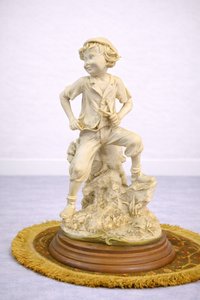 Porcelánová soška chlapce na skalce