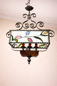 Kovový lustr s vitrážovým stínidlem a květinovými motivy, pochází ze stylu secese